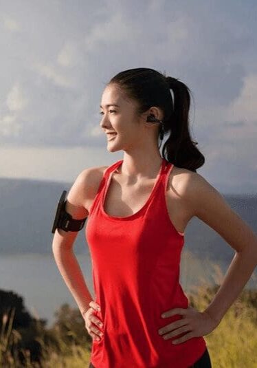 A woman in red shirt holding her hands on the side of her shoulder.